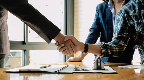 Real estate agent and customers shaking hands together celebrating finished contract after about home insurance and investment loan, handshake and successful deal