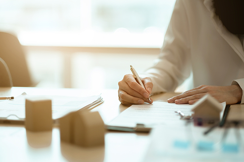 close-up view hands of businesswoman signing leasing home documents and have a apartment keys on paperwork.