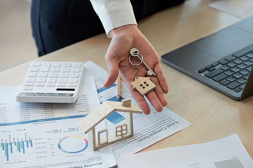 Mortgage concept. woman hand holding key with house shaped keychain. Real estate, moving home or renting property.