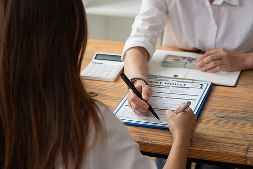 close up view hands of businessman signing leasing home documents and have a apartment keys on paperwork.