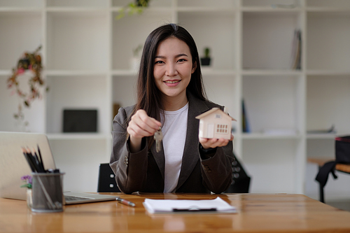 Real estate agent hand holding house model and keys.