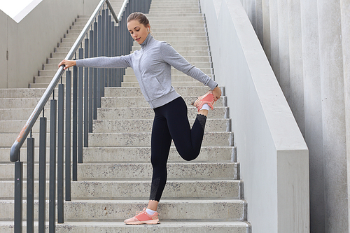 Portrait of fit and sporty young woman doing stretching outdoor.