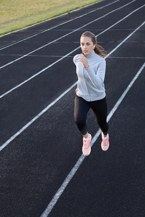 Runner athlete running on athletic track training her cardio in stadium. Jogging at fast pace for competition.