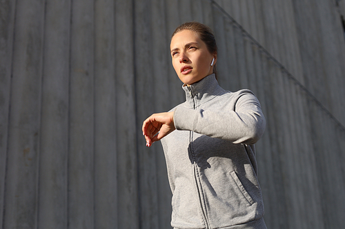 Young attractive sporty fitness woman running while exercising outdoors at sunset or sunrise in city.