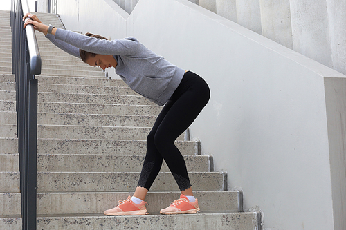 Portrait of fit and sporty young woman doing stretching outdoor.