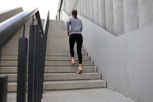 Rear view of runner athlete running on stairs. Woman fitness is jogging oudoors.