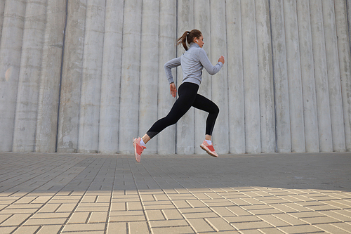 Young attractive woman with perfect slim body running outdoors. Fitness and running concept.