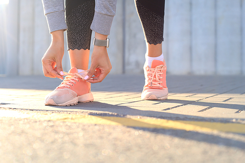 Closeup of unrecognizable sport woman tying sports shoes during evening run outdoors.