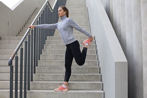 Portrait of fit and sporty young woman doing stretching outdoor.