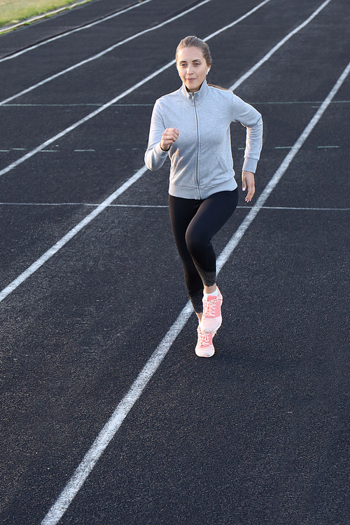 Runner athlete running on athletic track training her cardio in stadium. Jogging at fast pace for competition.