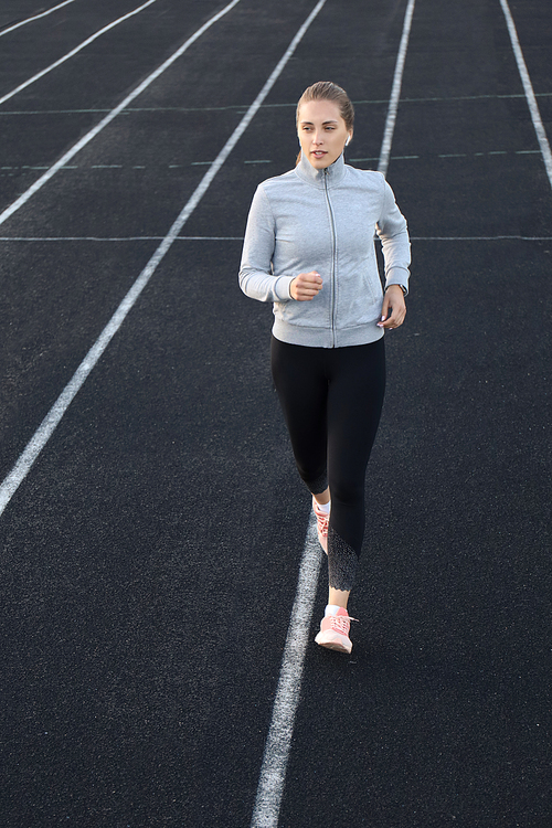 Runner athlete running on athletic track training her cardio in stadium. Jogging at fast pace for competition.