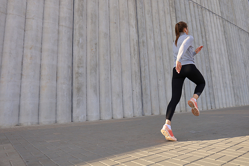 Young attractive woman with perfect slim body running outdoors. Fitness and running concept.