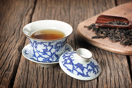 a cup of chinese tea, tea cup with tea leaves isolated on wooden plank