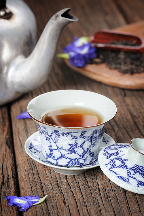 a cup of chinese tea, tea cup with tea leaves isolated on wooden plank