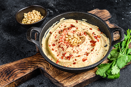 Hummus paste with chickpea and parsley in a bowl. Black background. Top view.