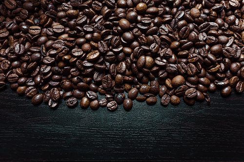 Shot from above of a lot of coffee grains over a dark wooden background