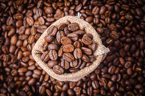 Top view of coffee beans in sack bag on coffee beans background.