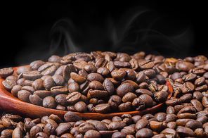 Coffee beans fresh roast with smoke on black background.