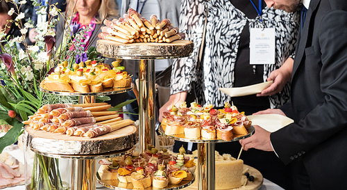 Businesspeople at banquet lunch break at business conference meeting. Assortment of canapes, small pieces of bread or pastry with a savory topping, and finger food on table.