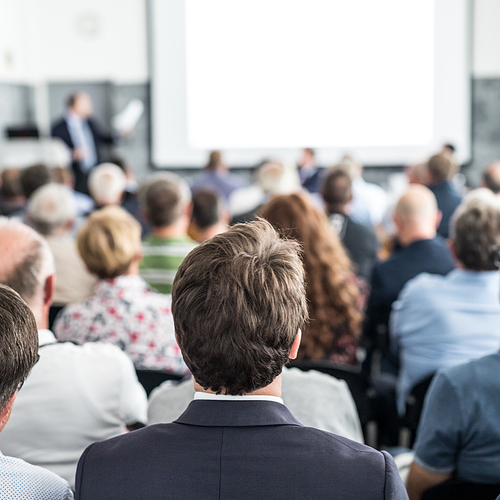 Speaker giving a talk in conference hall at business event. Audience at the conference hall. Business and Entrepreneurship concept. Focus on unrecognizable people in audience.