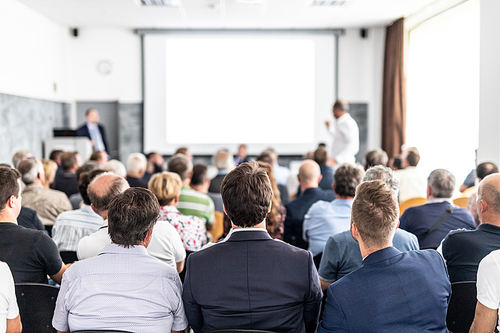 I have a question. Group of business people sitting at the chairs in conference hall. Businessman standing up asking a question. Conference and Presentation. Business and Entrepreneurship.