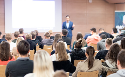 Speaker giving a talk in conference hall at business event. Audience at the conference hall. Business and Entrepreneurship concept. Focus on unrecognizable people in audience.