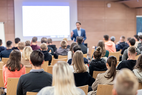 Speaker giving a talk in conference hall at business event. Audience at the conference hall. Business and Entrepreneurship concept. Focus on unrecognizable people in audience.