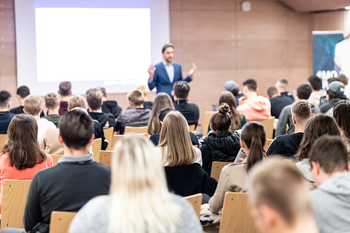 Speaker giving a talk in conference hall at business event. Audience at the conference hall. Business and Entrepreneurship concept. Focus on unrecognizable people in audience.