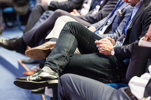 Row of unrecognizable business people sitting in conference hall at business event. Audience at business seminar. Business and Entrepreneurship concept.