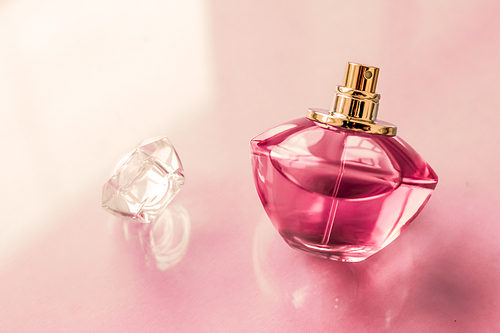 Perfumery, spa and branding concept - Pink perfume bottle on glossy background, sweet floral scent, glamour fragrance and eau de parfum as holiday gift and luxury beauty cosmetics brand design