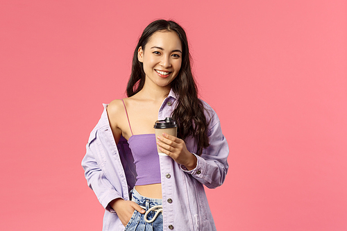 Lifestyle, modern people and beauty concept. Sassy good-looking asian girl chilling with friends at favorite cafe, grab take-away beverage, drinking coffee and smiling camera, pink background.