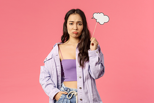 Holidays, lifestyle and people concept. Portrait of gloomy, sulking asian girl dont have any ideas, holding thinking cloud stick and look upset camera as cant figure out plan, pink background.