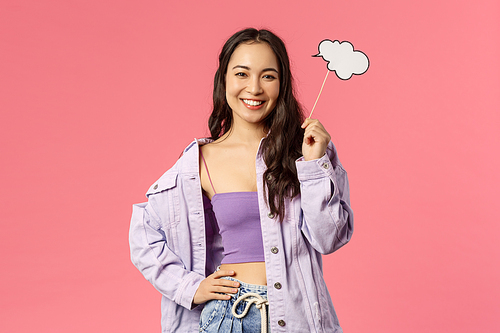 Holidays, lifestyle and people concept. Portrait of creative charismatic young asian girl in stylish outfit holding a cloud stick, comment, imaging something, having lots ideas, smiling pleased.