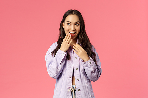Lifestyle, spring and beauty concept. Portrait of stylish young pretty girl have an idea, giggle, smile and cover mouth, look upper left corner devious and thoughtful, have plan, pink background.