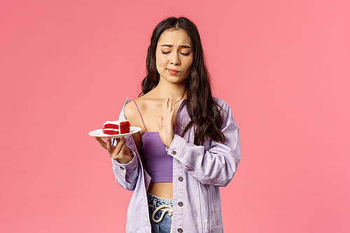 No thank you calories. Portrait of attractive asian girl taking care of her looks, saying no to delicious dessert, smirk show stop sign to cake, restrain herself eat after six, pink background.