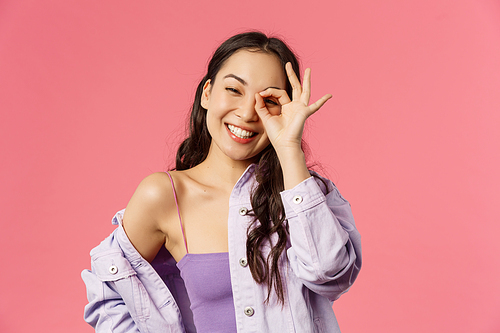 Close-up portrait of carefree, optimistic good-looking asian girl in stylish outfit, korean female student have positive happy mood, show okay no problem sign over eye, grinning joyfully.