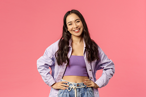 Lifestyle, fashion and people concept. Portrait of stylish modern young female, korean girl in crop-top and denim jacket, ready for party, standing confident and relaxed, happy smiling.