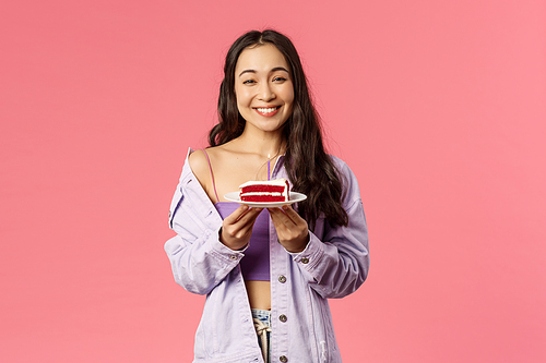 Eating-out, food and people concept. Portrait of joyful lovely, modern asian girl holding plate with cake, eat favorite dessert, laughing and smiling, likes sweet, standing pink background.