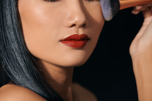 Portrait of young Asian woman applying lipstick