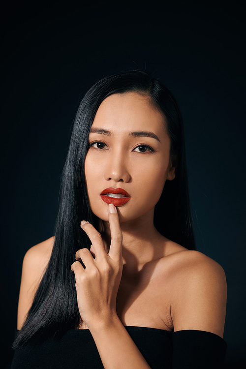 Face of the beautiful woman with long hair posing at studio over dark background