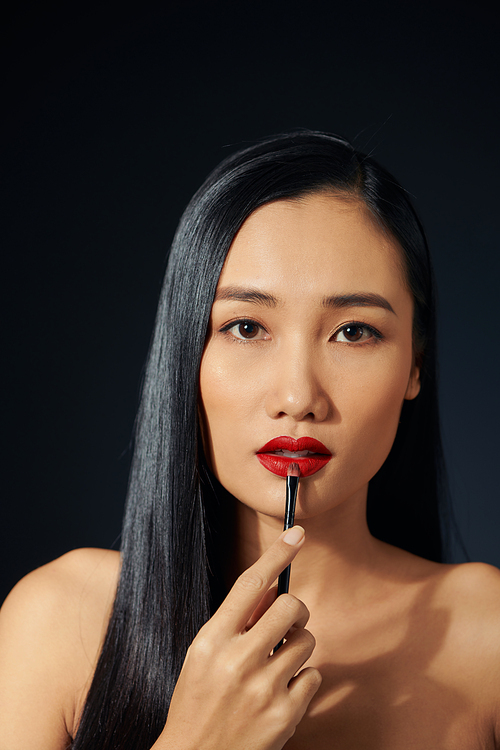 Beautiful woman paints lips with lipstick. Beautiful woman face. Makeup detail. Beauty girl with perfect skin. Red lips and nails manicure