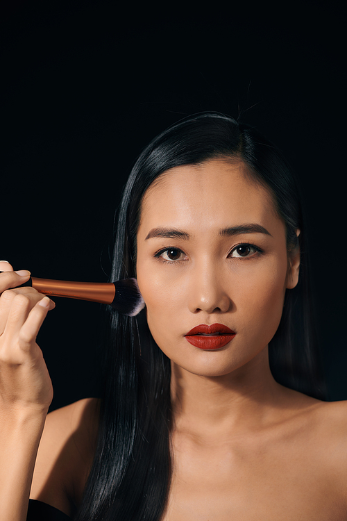 Portrait of young Asian woman applying lipstick
