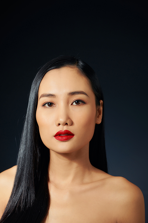 Asian female model with red make up against black background.