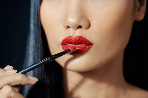 Young woman applying lipstick with an applicator