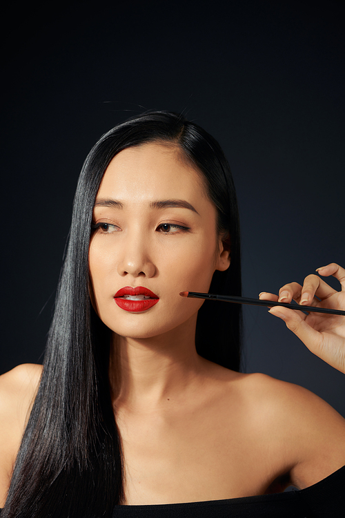 Beautiful woman paints lips with lipstick. Beautiful woman face. Makeup detail. Beauty girl with perfect skin. Red lips and nails manicure