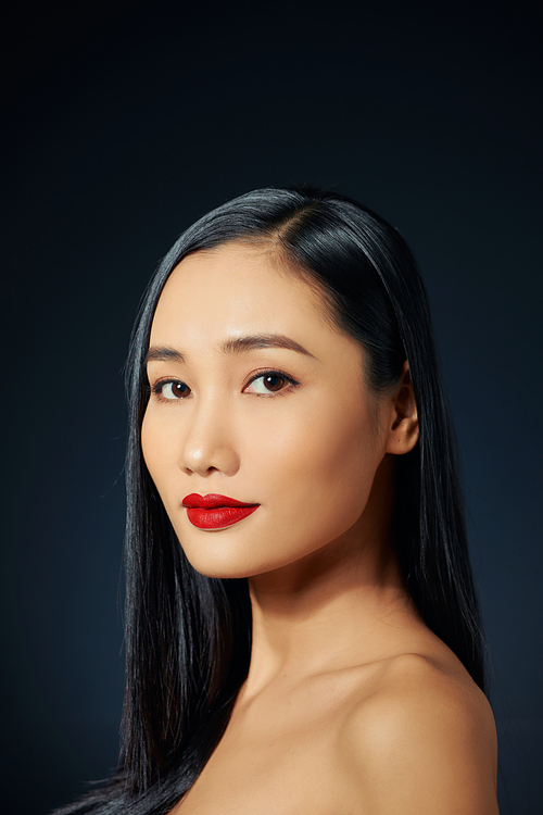 Asian female model with red make up against black background.