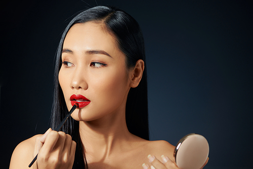 Closeup portrait of beautiful young woman with makeup brushes. Red lips. Isolated over blachbackground.