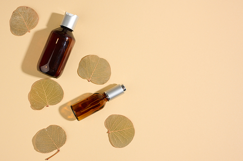 glass cosmetic brown bottles on a beige background. Cosmetics SPA branding mockup, top view