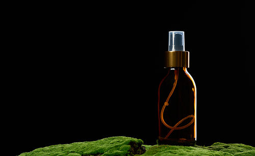 brown glass spray bottle stands on green moss. Cosmetics SPA branding. Packaging, advertising and product promotion, mock up
