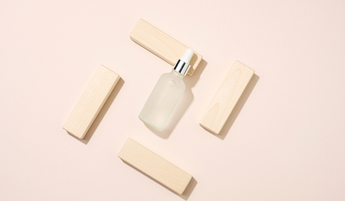 white glass bottle with pipette stands on a beige background. Cosmetics SPA branding. Packaging for gel, serum, advertising and product promotion, mock up